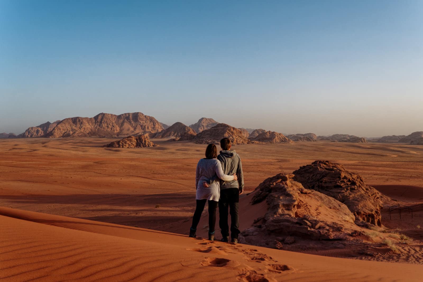 Ein Pärchen von hinten (wir) in der Wüste Wadi Rum bei Sonnenuntergang.